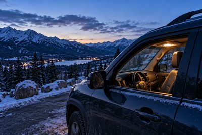 A parked SUV beside a snow-covered Colorado mountain road at twilight.